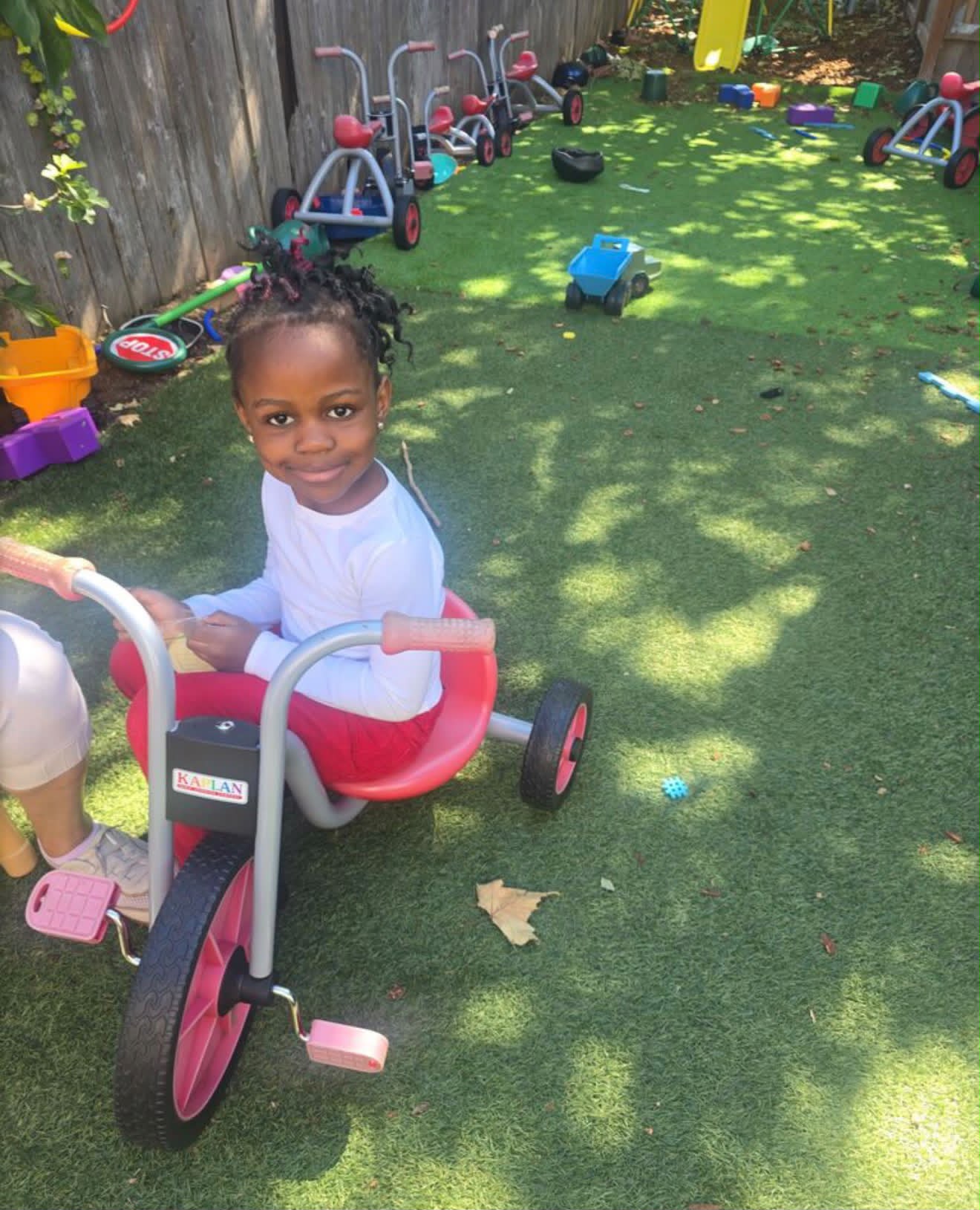 Young learner smiling on a tricycle in the playground